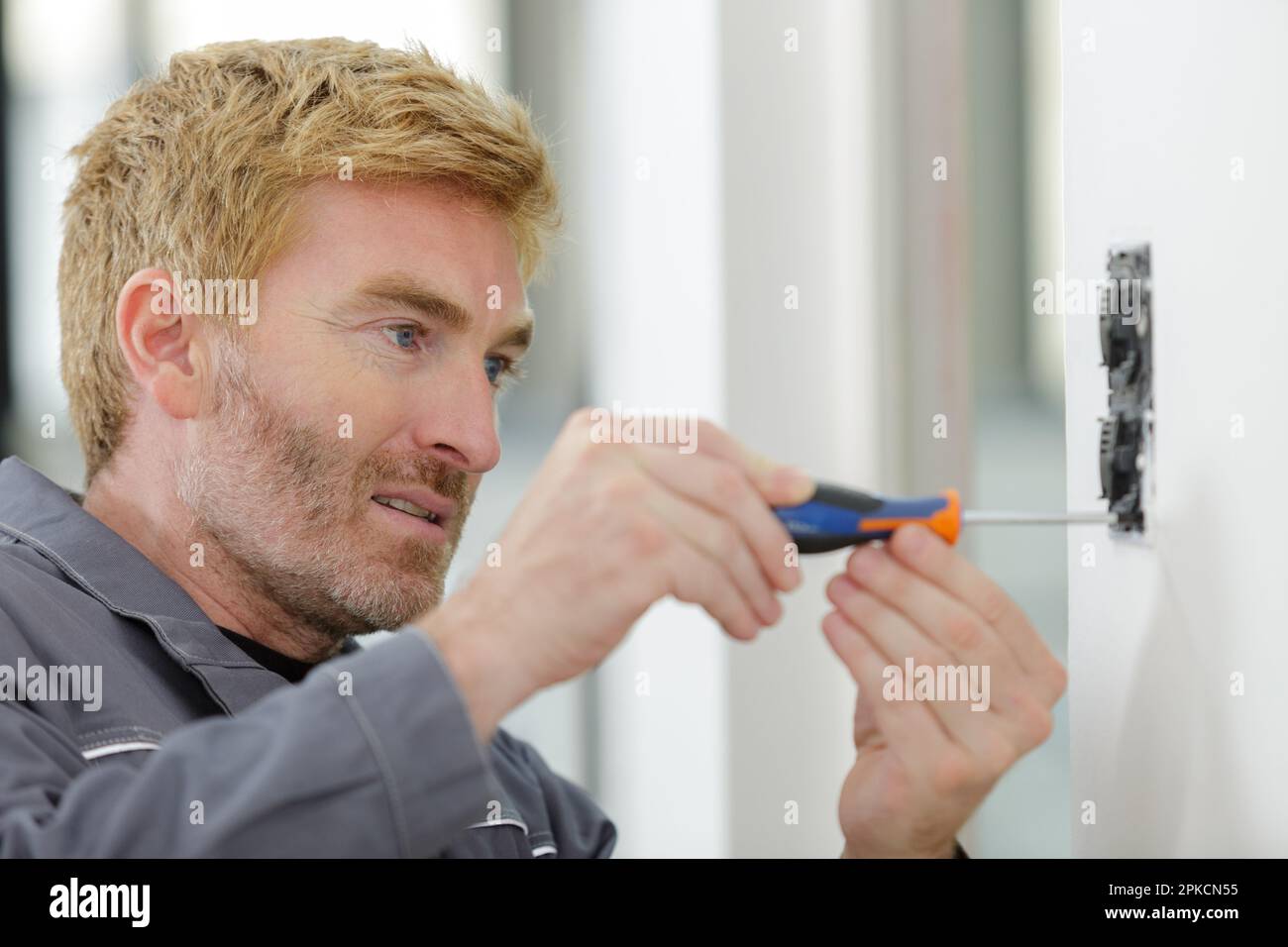 electrician putting sockets on wall Stock Photo