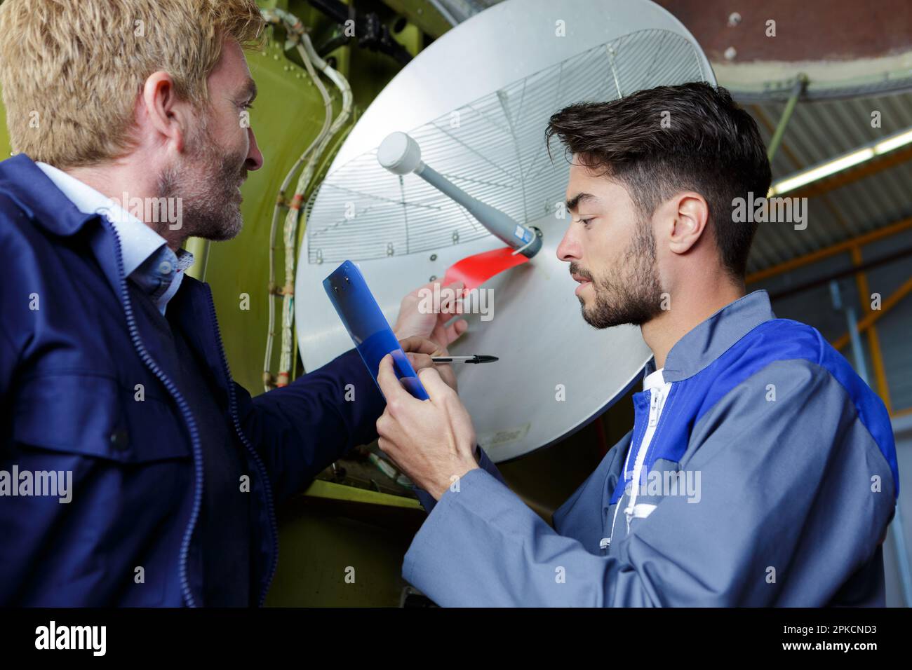 worker technician fitting tv satellite dish to house roof Stock Photo