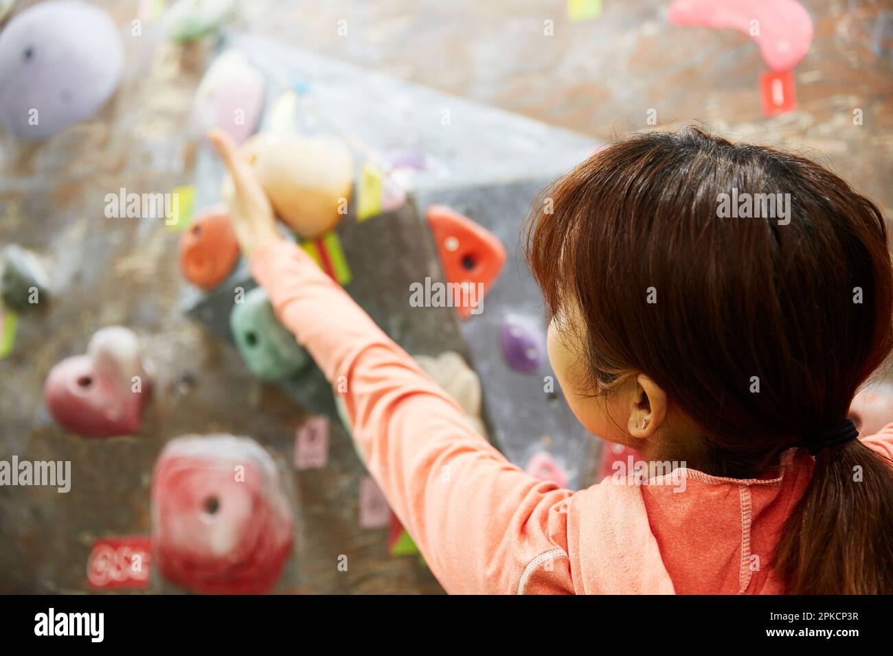 Woman reaching for the next hold in bouldering Stock Photo