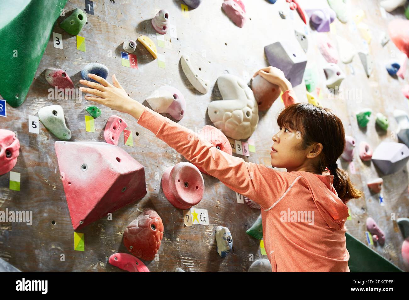 Woman reaching for the next hold while bouldering Stock Photo