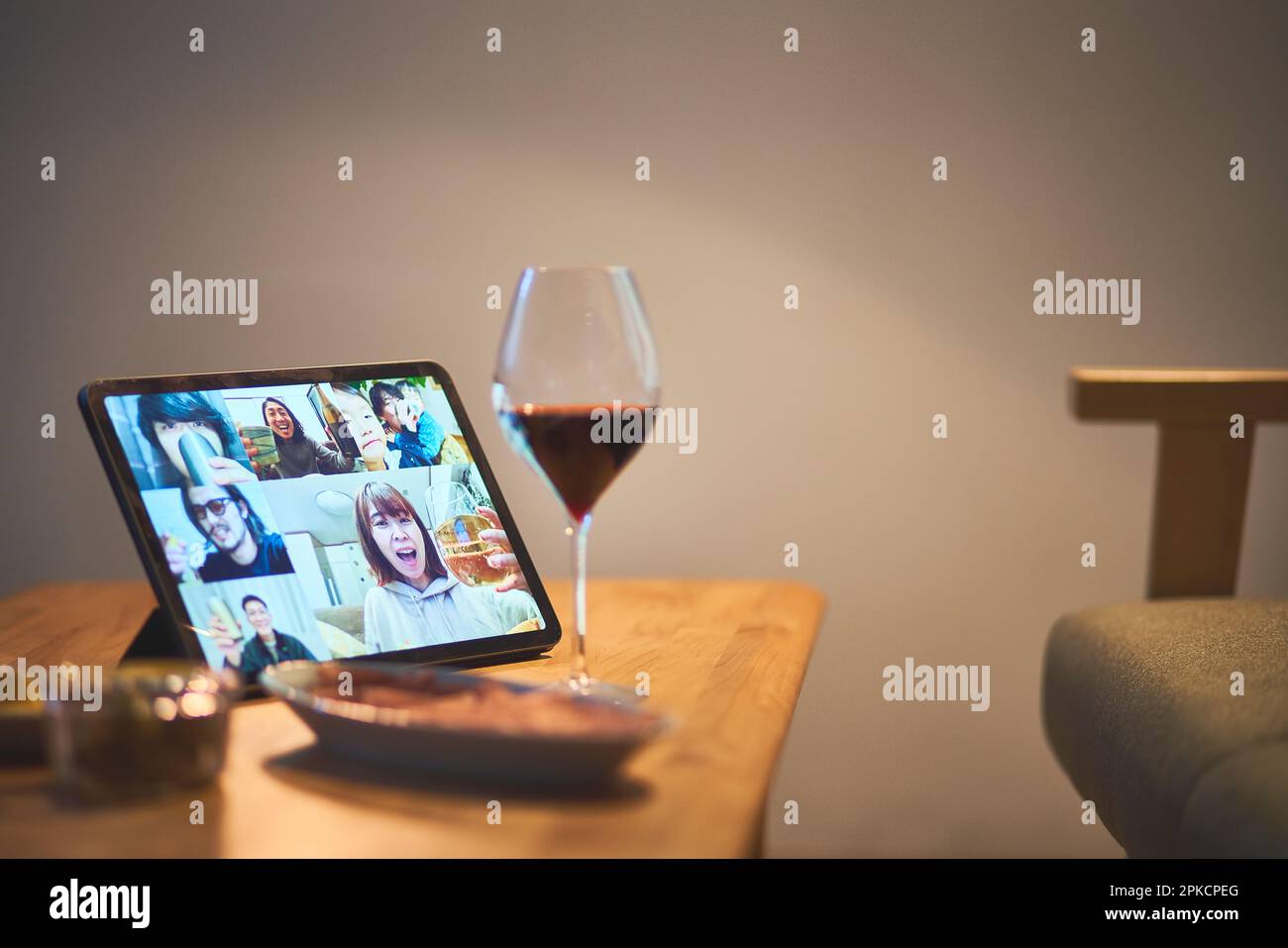 Remote drinking computer screen, red wine and snacks Stock Photo