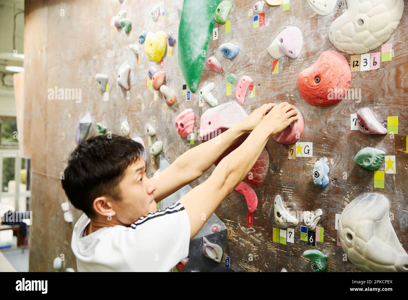 Man grasping the start hold with both hands while bouldering Stock Photo