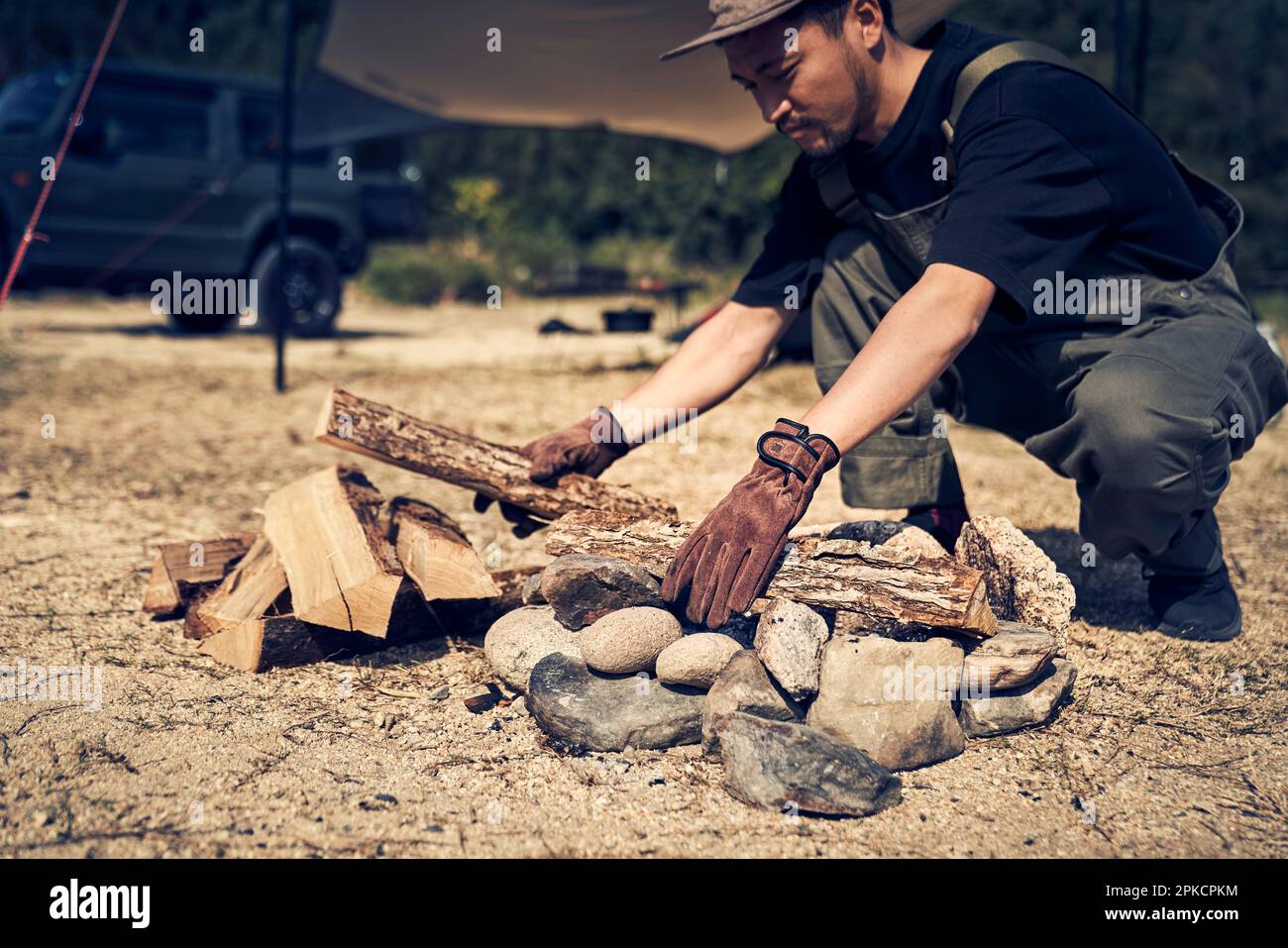 Man placing firewood in fire pit Stock Photo Alamy