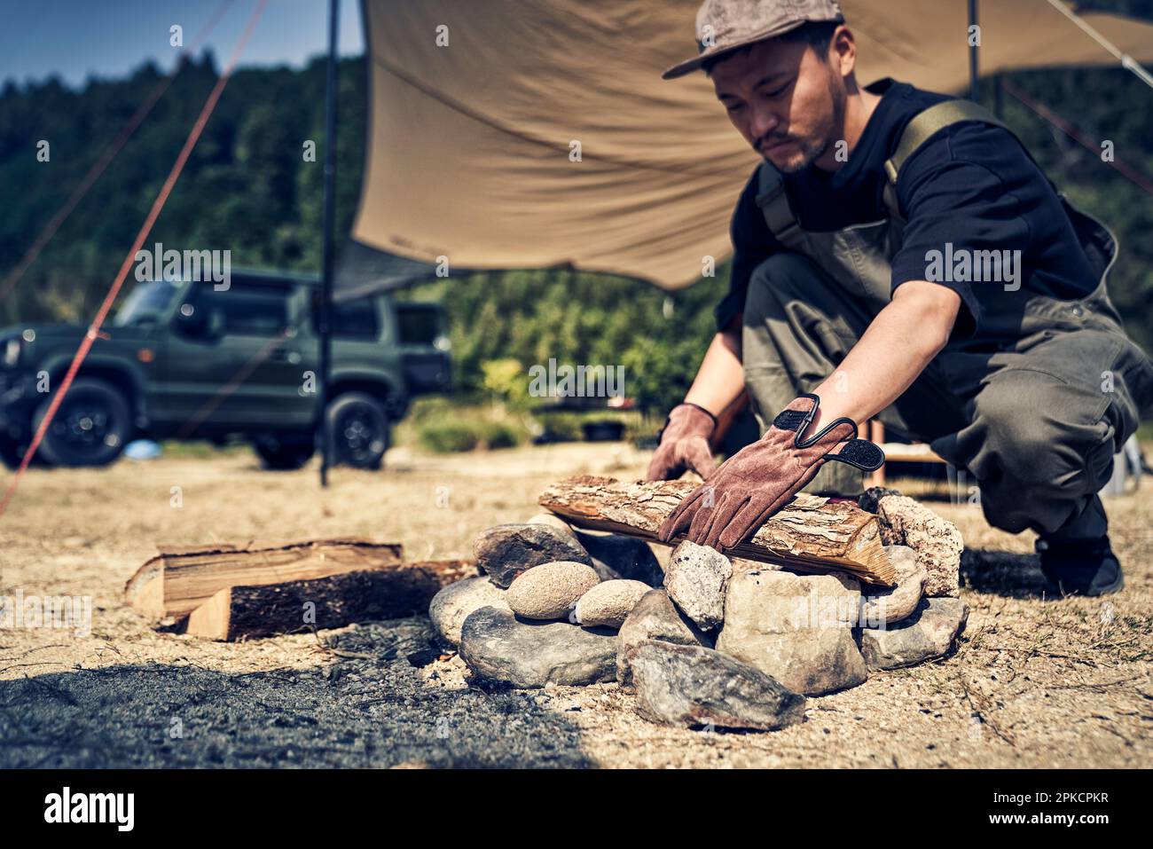 Man placing firewood in fire pit Stock Photo Alamy