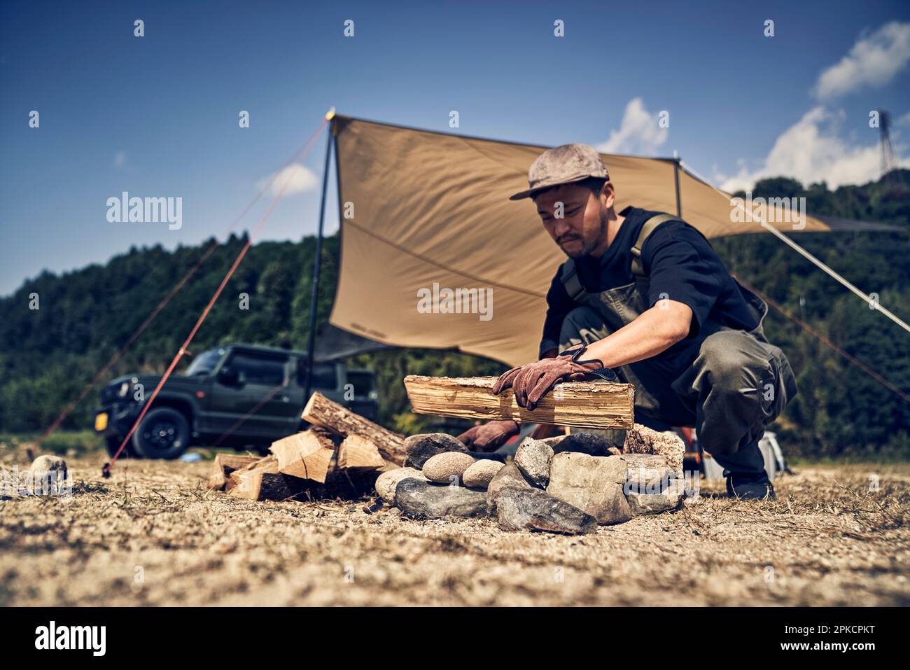 Man placing firewood in fire pit Stock Photo Alamy