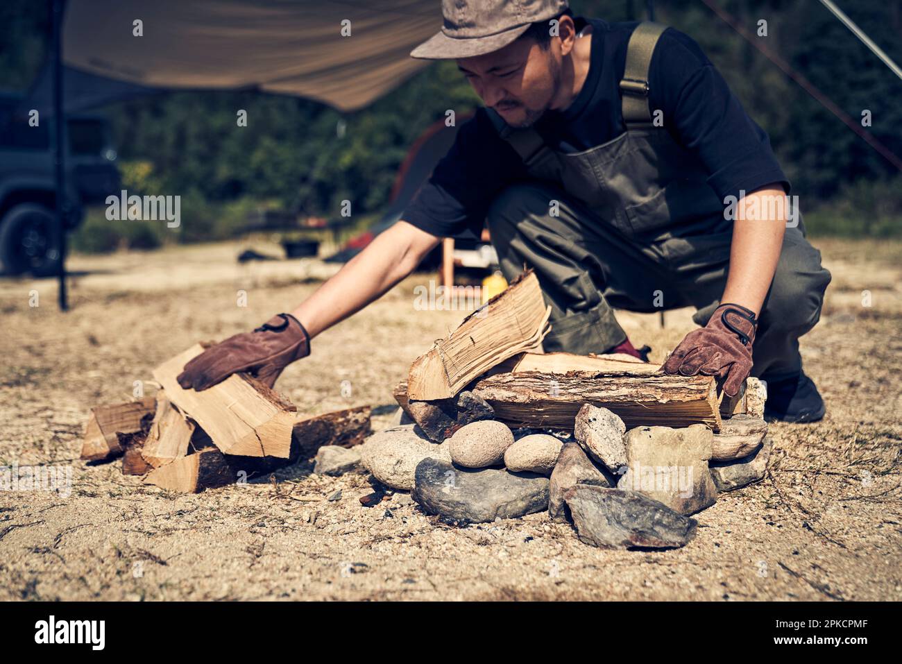 Man placing firewood in fire pit Stock Photo Alamy