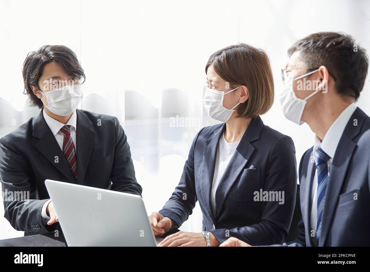 Office worker talking with a computer wearing a mask in his office Stock Photo