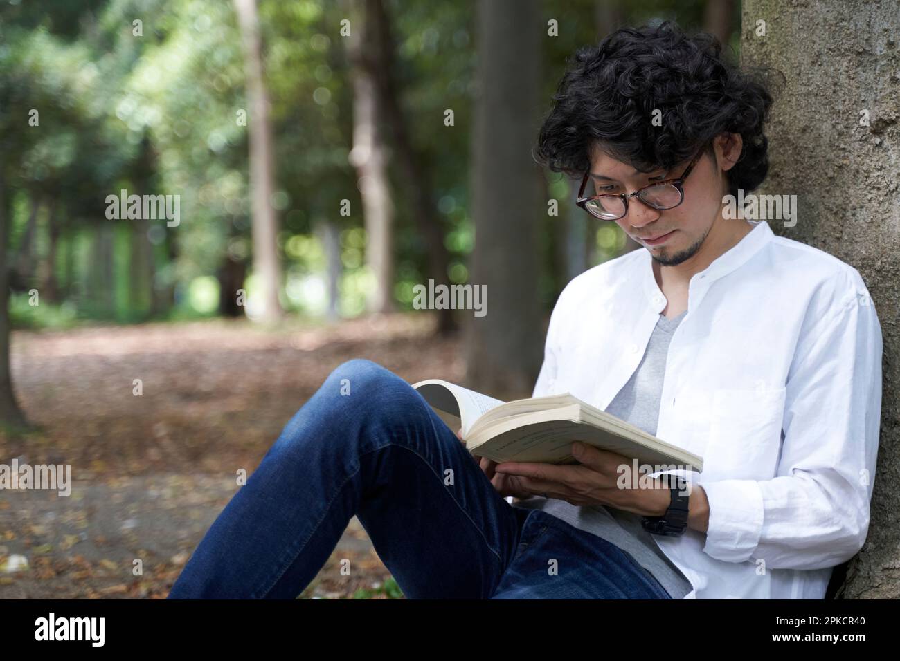 Man reading book sitting on tree back Stock Photo