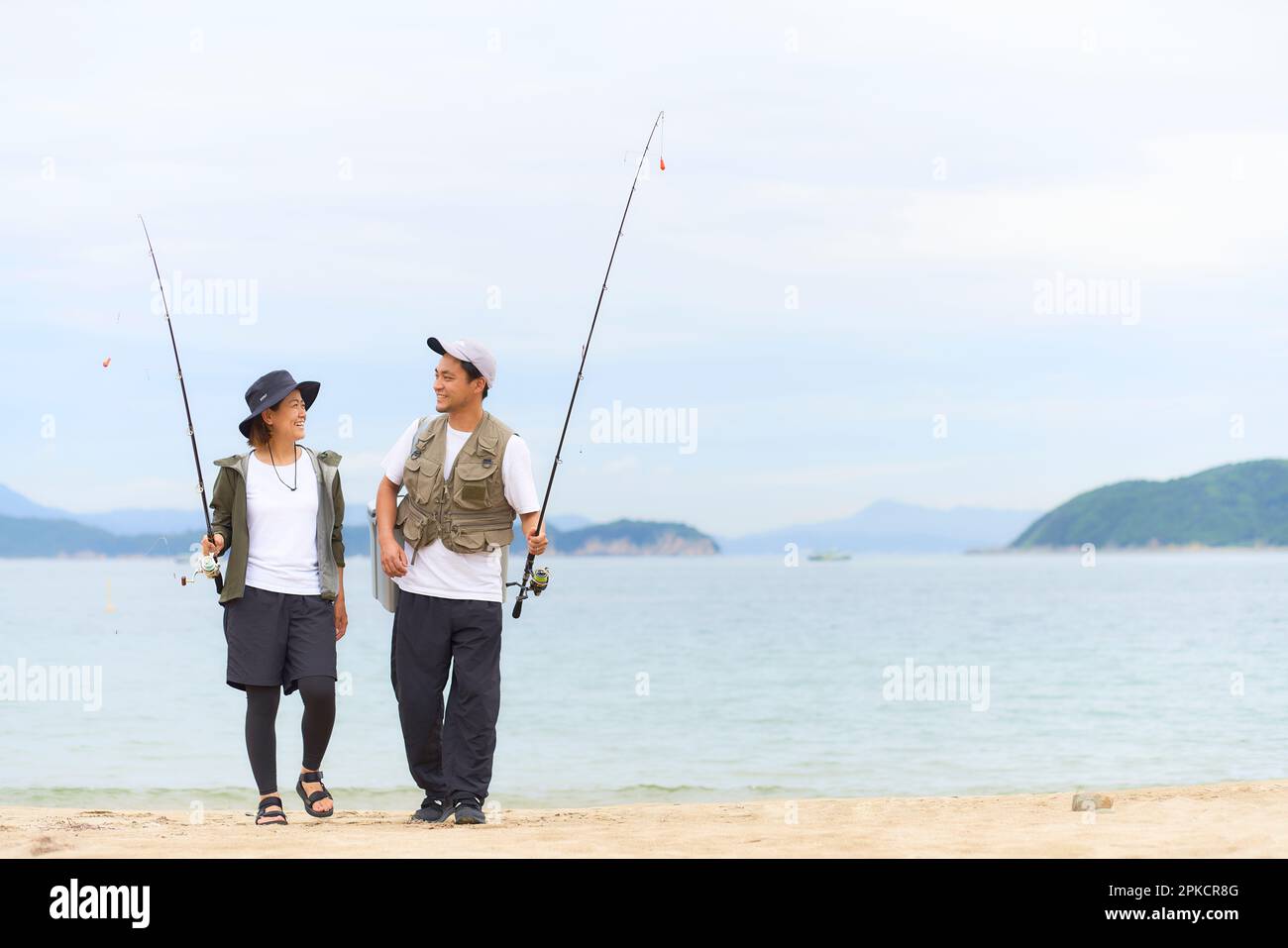 Men and women walking on the beach with fishing gear Stock Photo