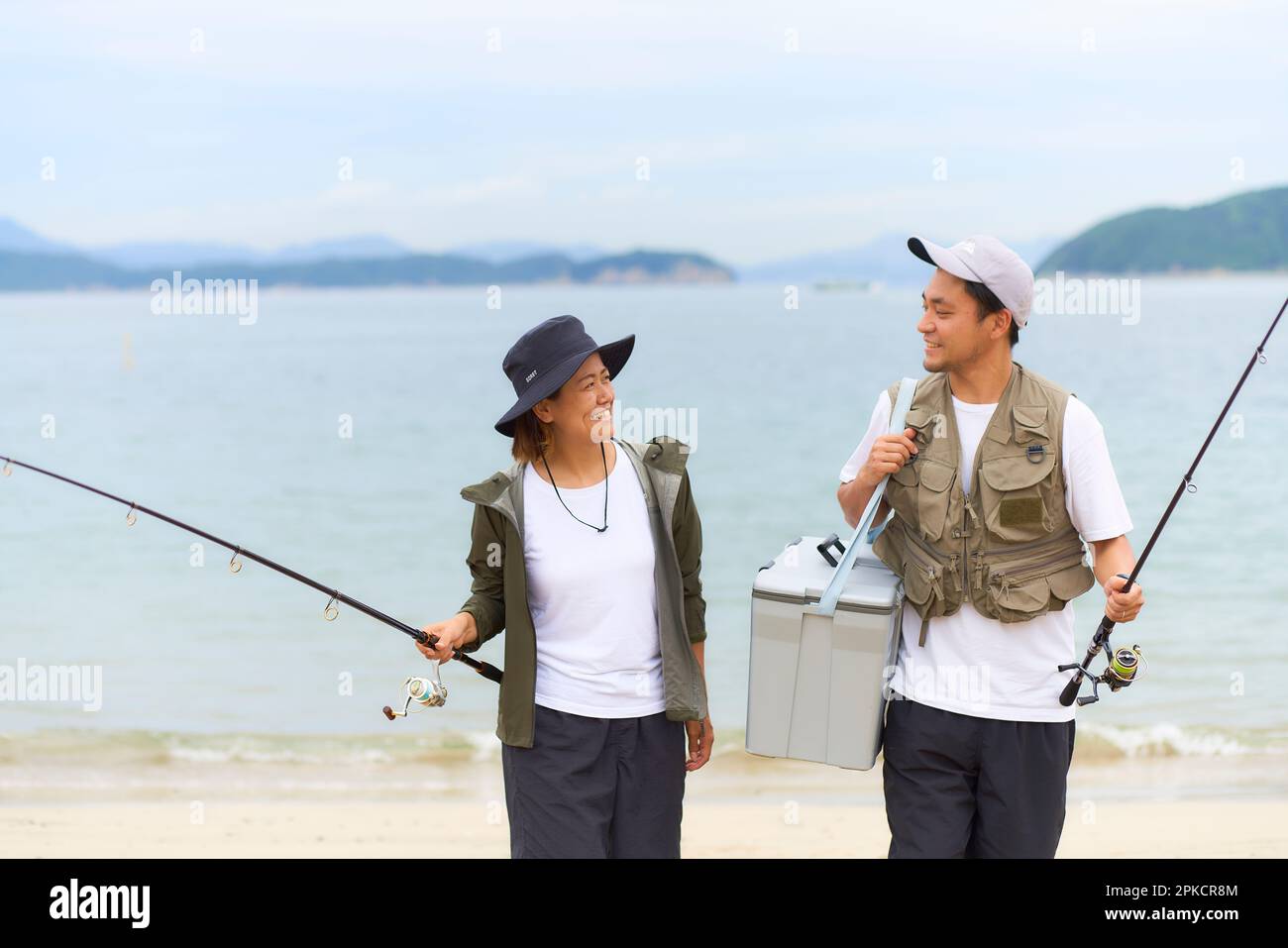 Men and women walking on the beach with fishing gear Stock Photo