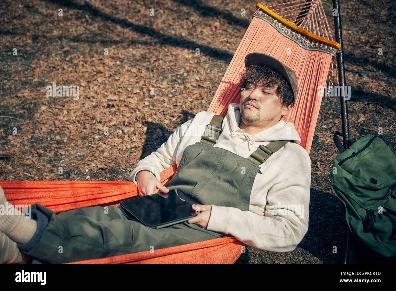 Man operating tablet device in hammock Stock Photo