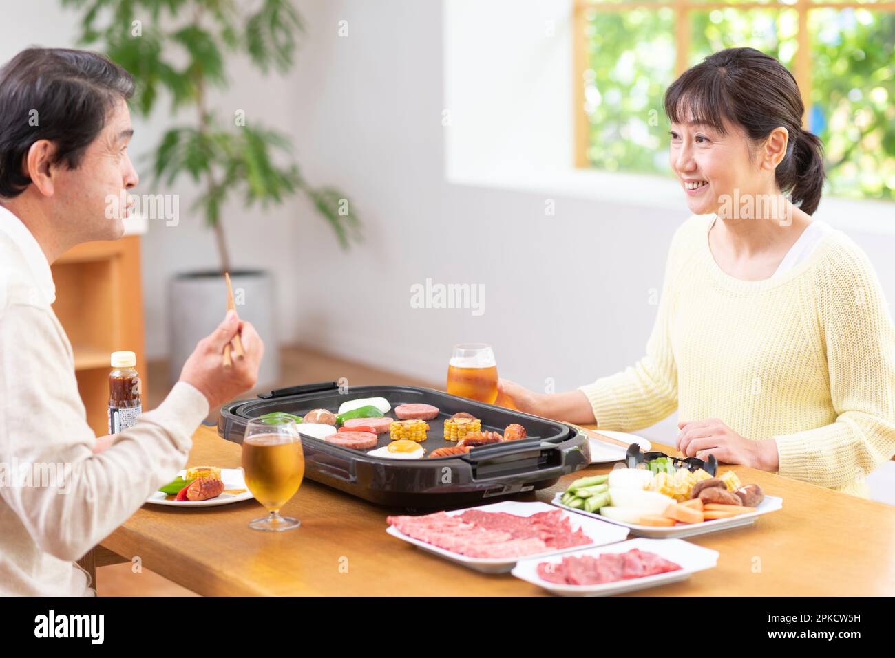A middle-aged couple eating Yakiniku with draft beer Stock Photo