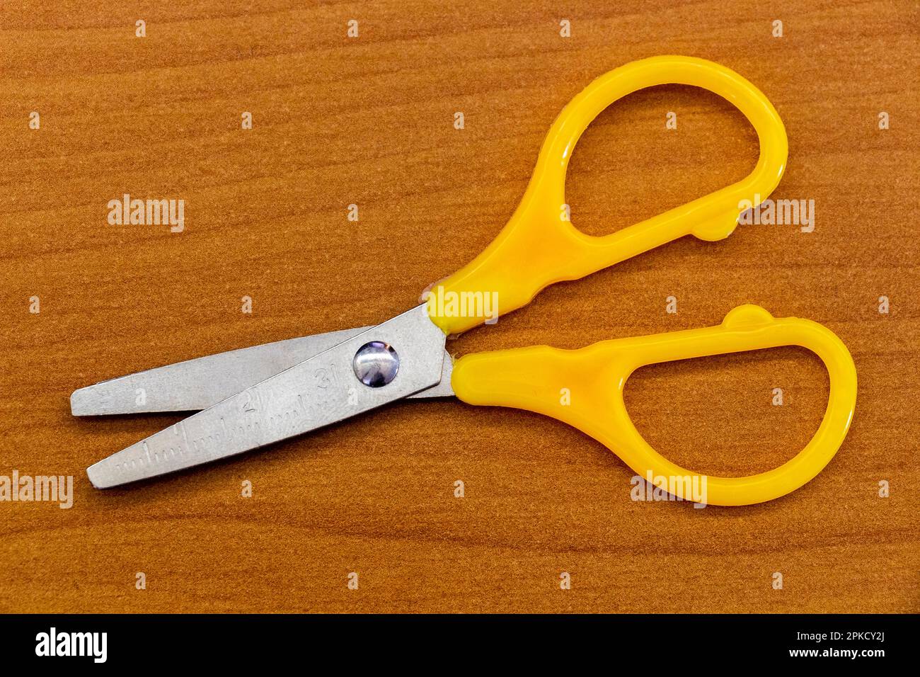 Yellow stationery scissors on the surface of the office table. Stock Photo