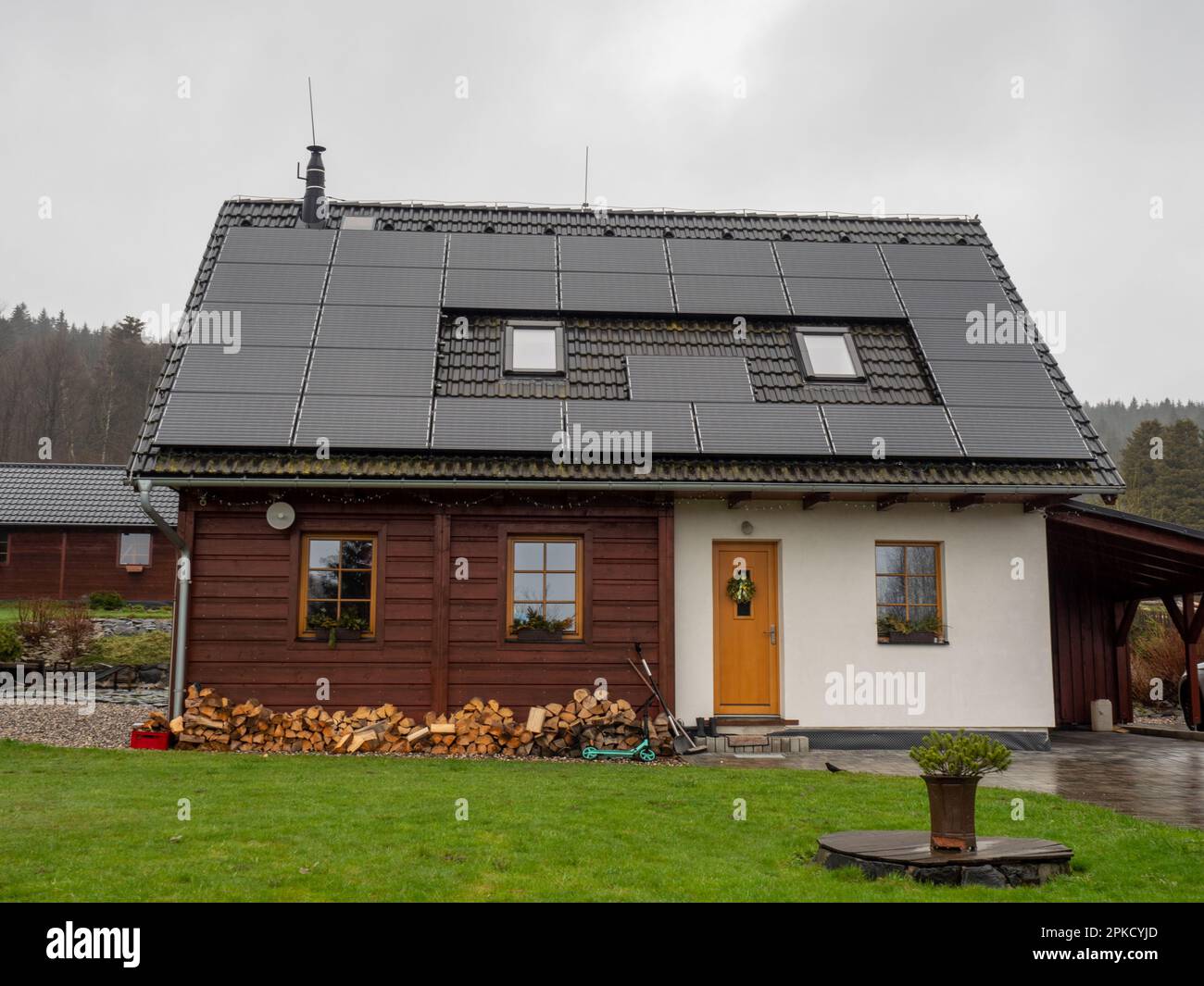 Solar panel on  black roof with small roof windows against cloudy sky.  Dark rainy day. Stock Photo