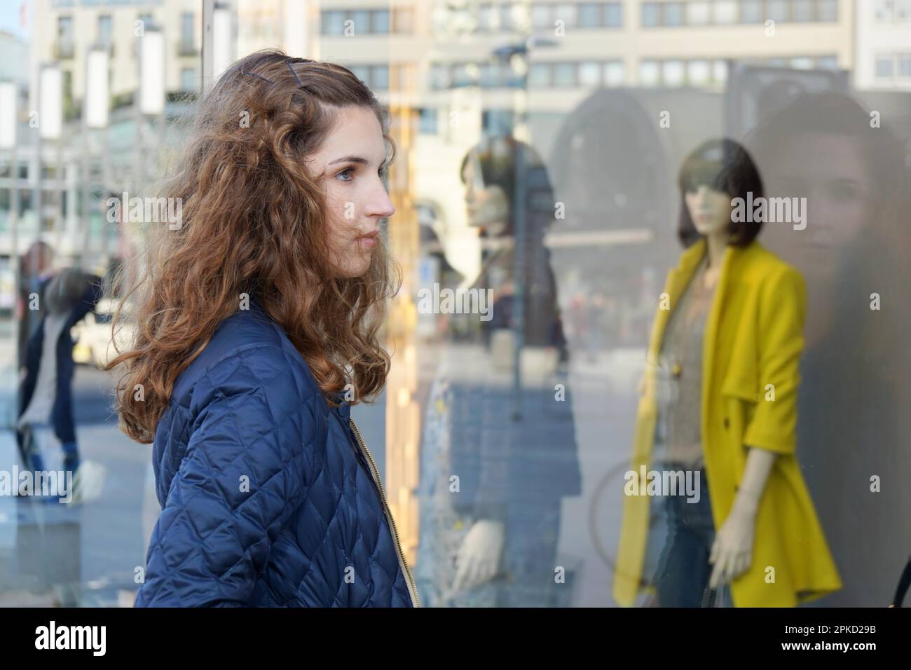 young woman looking at fashion display in shop window Stock Photo