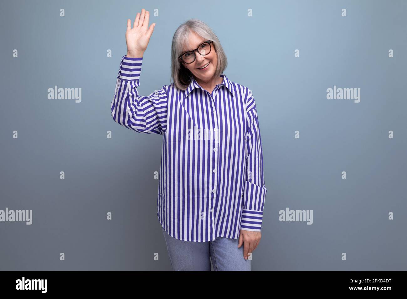 successful cheerful 60s middle aged woman in trendy shirt on bright studio background with copyspace Stock Photo