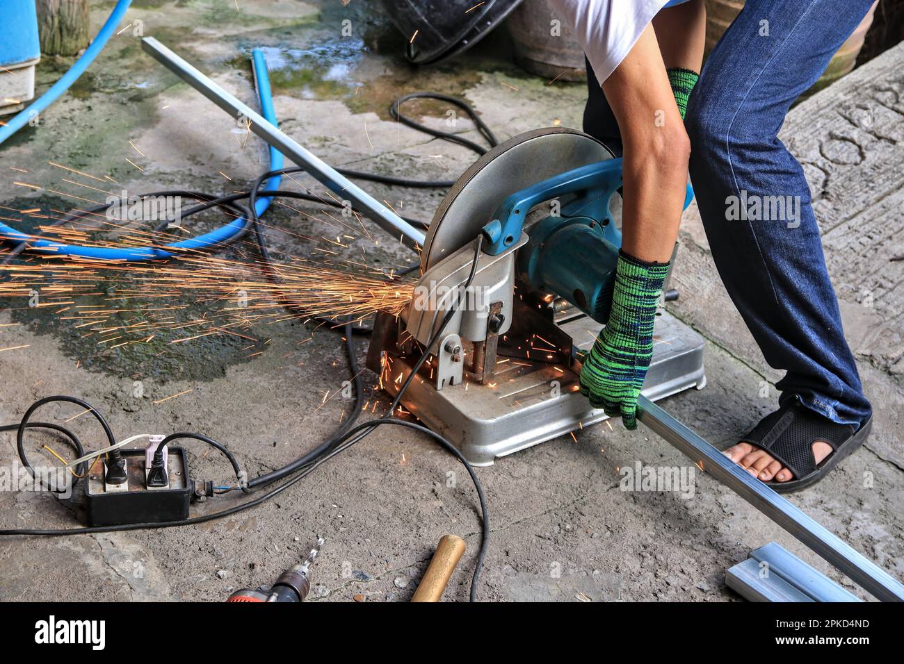 A worker uses a steel cutter to create a large number of sparks. and place various tools recklessly placed near a water source may cause a short circu Stock Photo