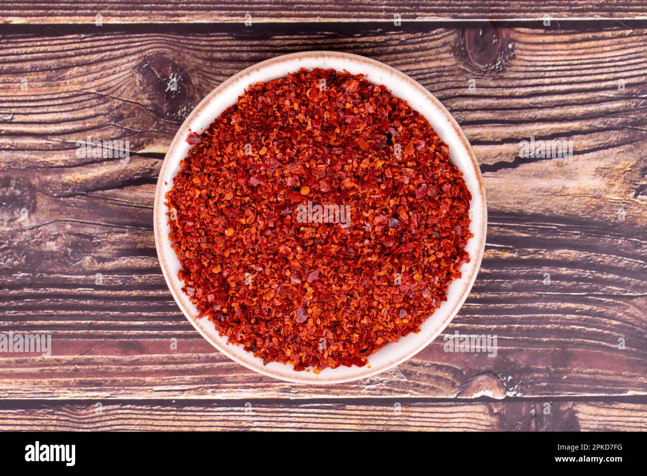 Dried red pepper flakes. Spice chili pepper flakes on wood background