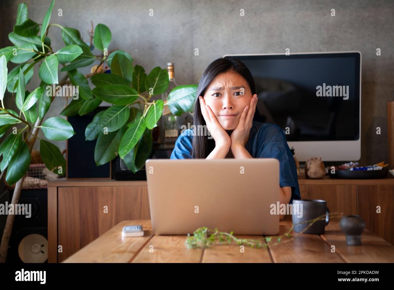 Woman in front of laptop computer looking troubled Stock Photo