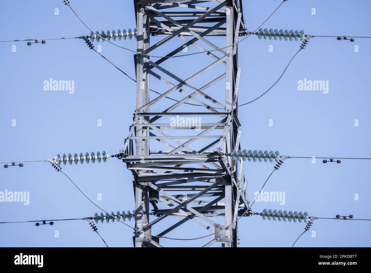 Lattice-type steel tower is under blue sky as a part of high-voltage line. Overhead power line details Stock Photo