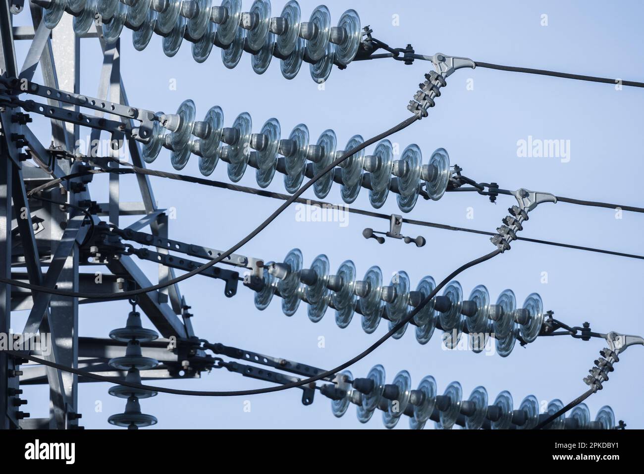 Overhead power line details are under blue sky on a daytime. High voltage insulators and wires Stock Photo