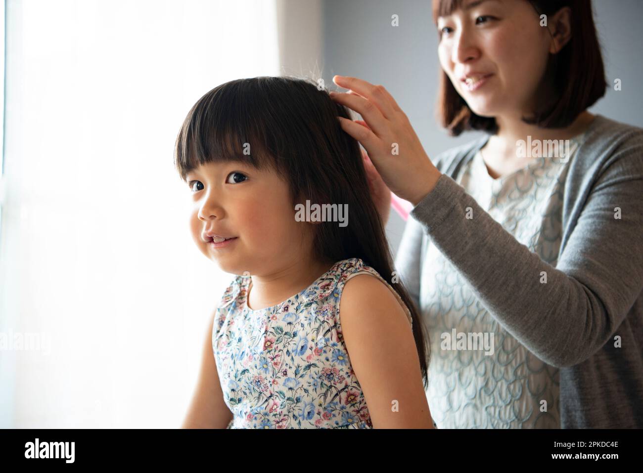 Mother combing girl's hair Stock Photo