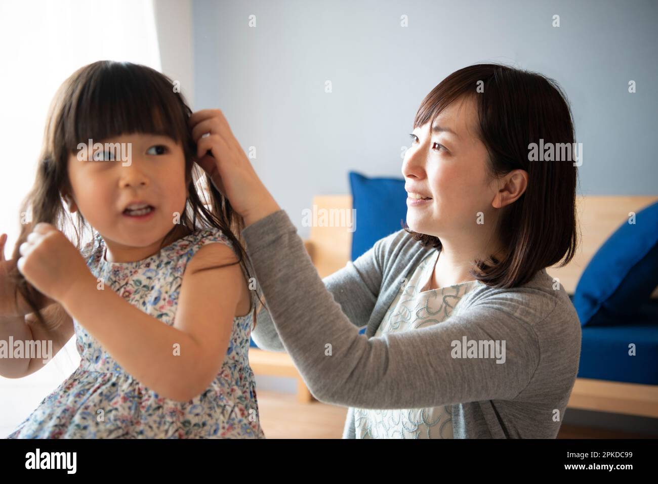 Mother tying girl's hair Stock Photo