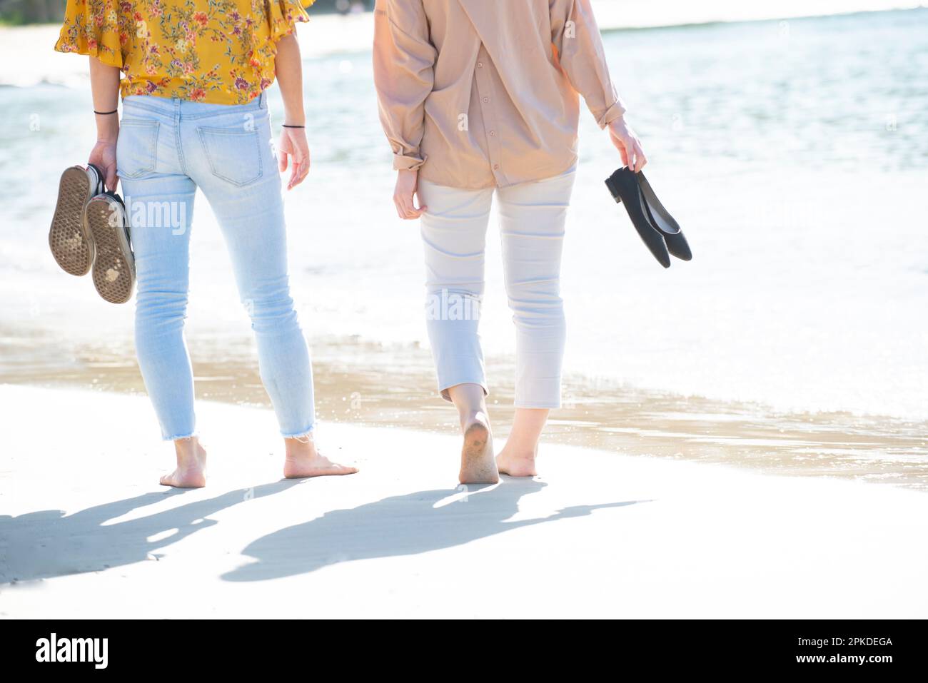 2 women walking barefoot on the beach Stock Photo - Alamy