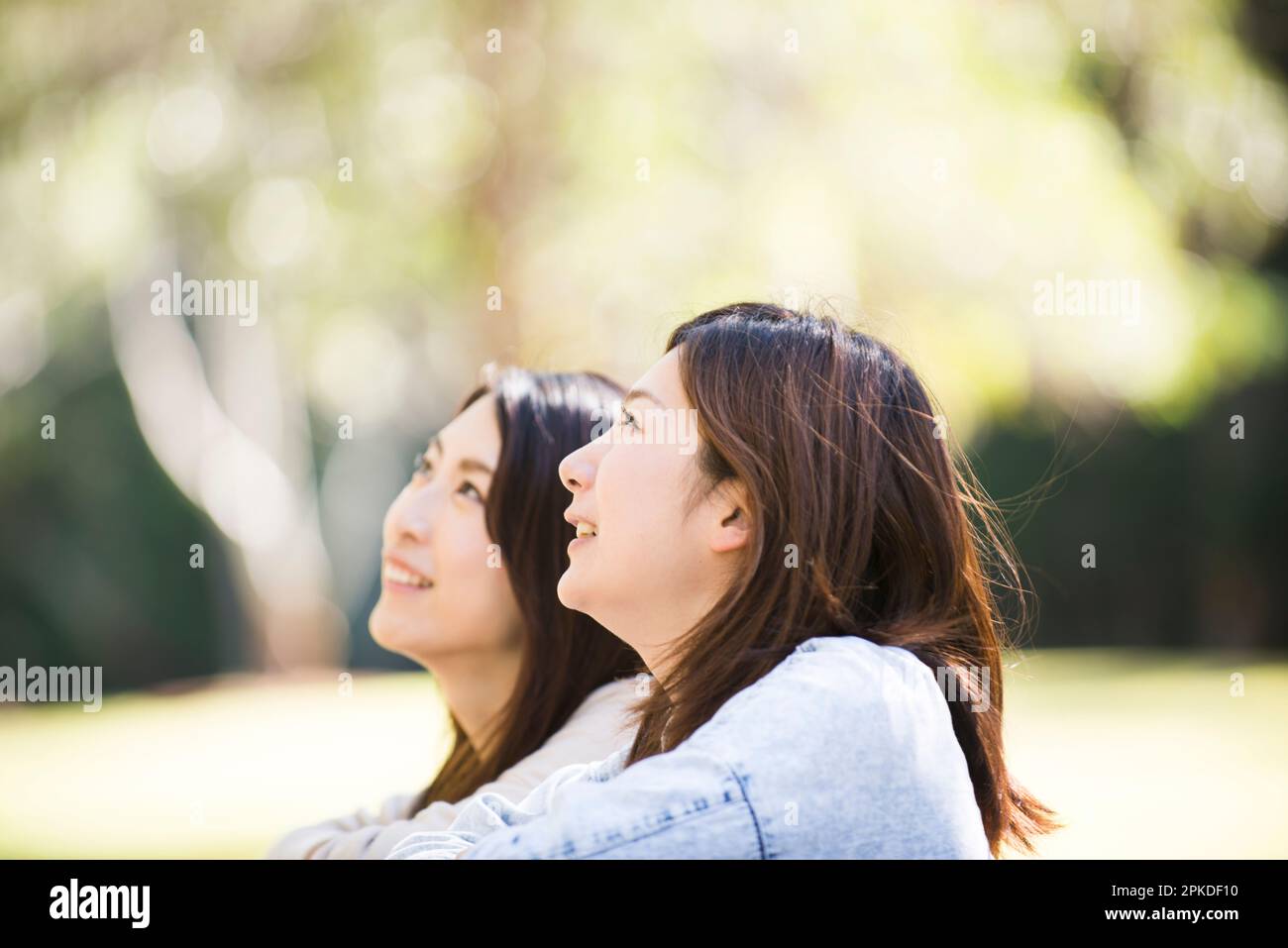 Two women looking up at the sky in green Stock Photo
