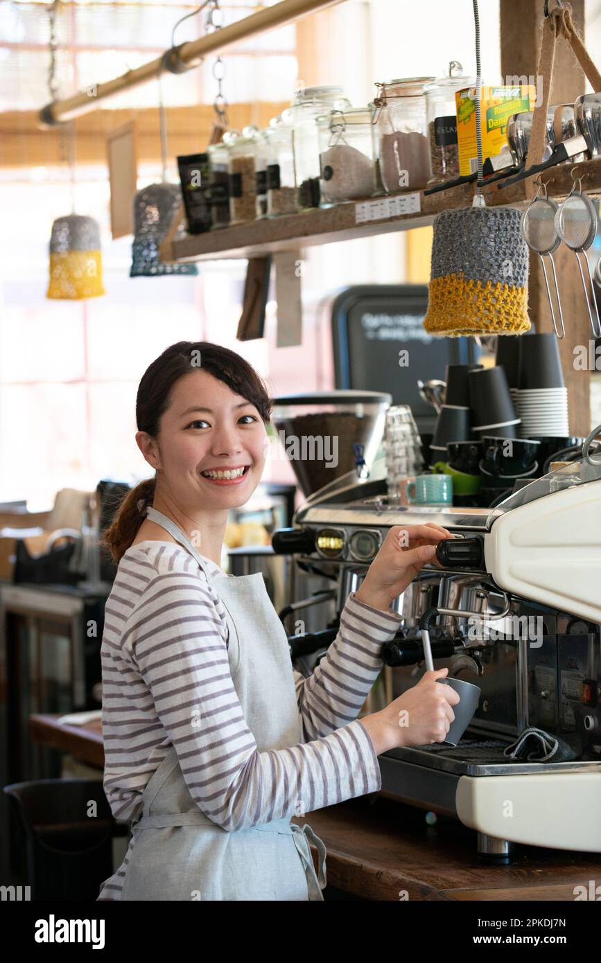 Woman of the sales clerk touching the espresso machine with a smile ...