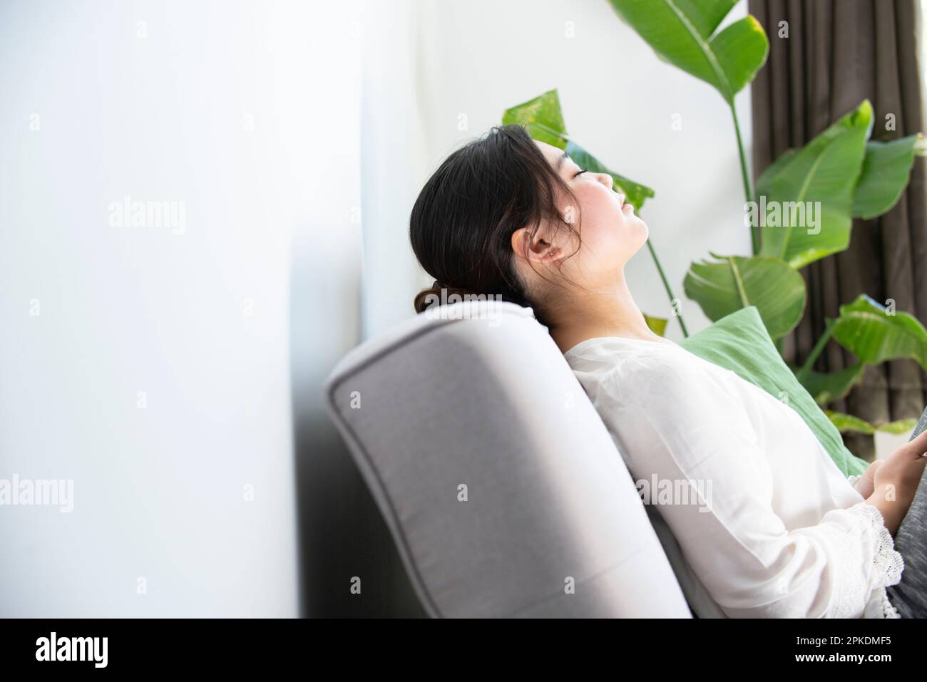 Woman sitting on the couch with her eyes closed Stock Photo - Alamy
