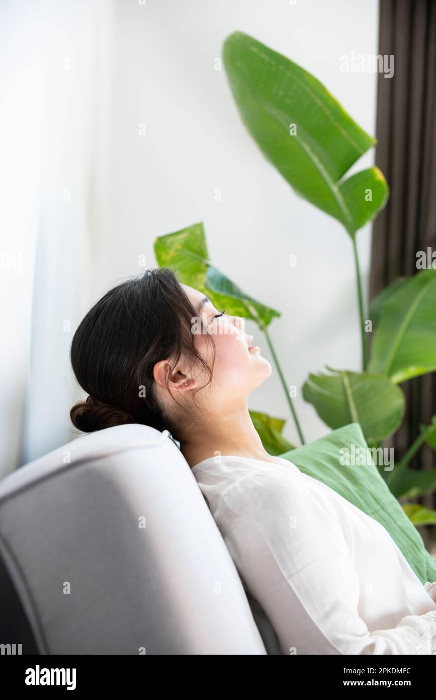 Woman sitting on the sofa with her eyes closed Stock Photo - Alamy