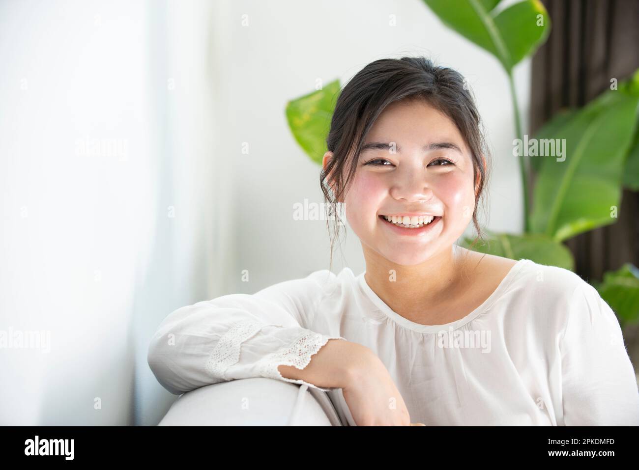 Woman sitting on couch indoors hi-res stock photography and images - Alamy