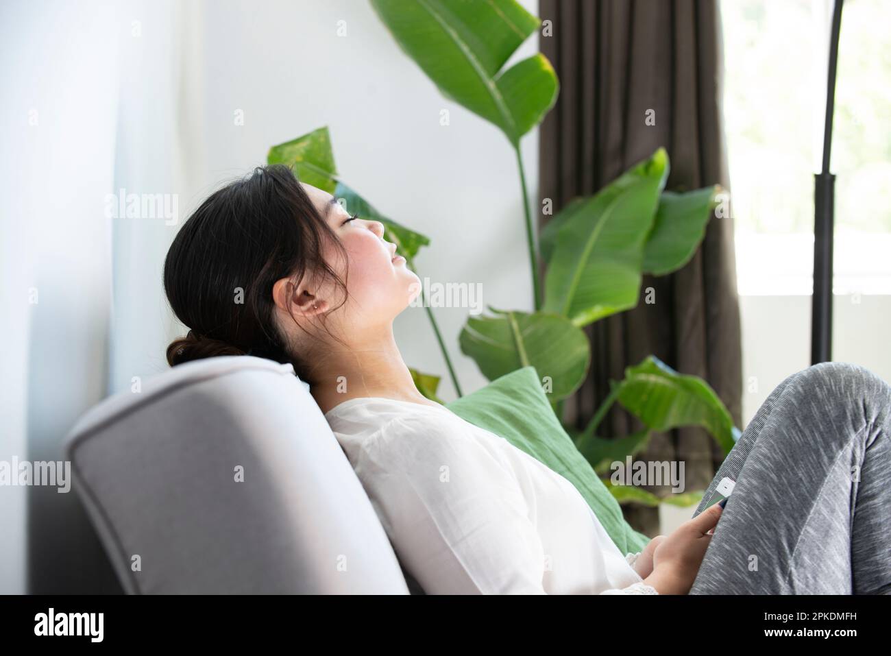 Woman sitting on the couch with her eyes closed Stock Photo - Alamy