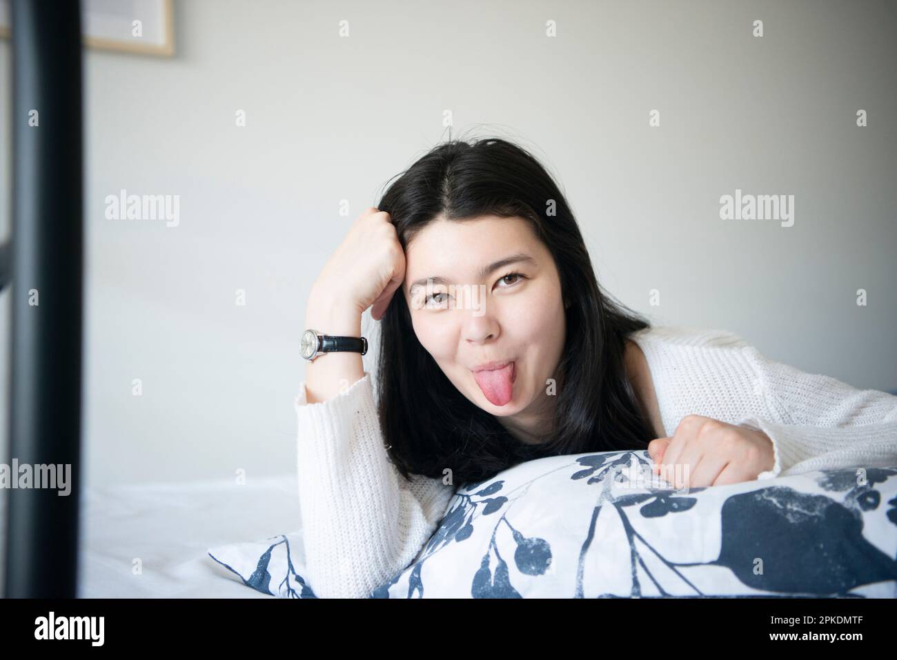 Woman lying on bed and sticking out her tongue Stock Photo Alamy