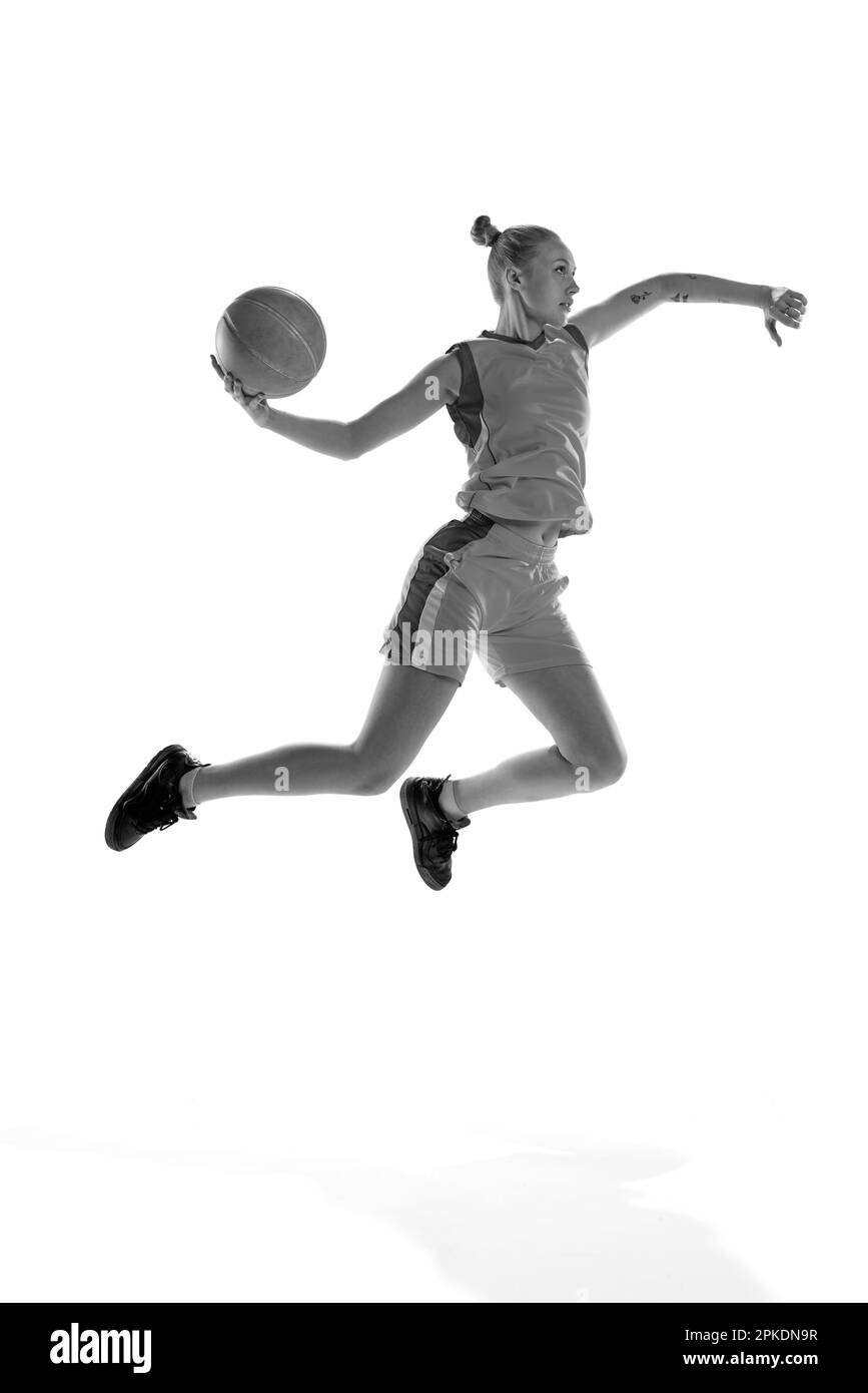 Black and white image of young sportive girl during basketball game, playing, training against white studio background. Concept of professional sport Stock Photo