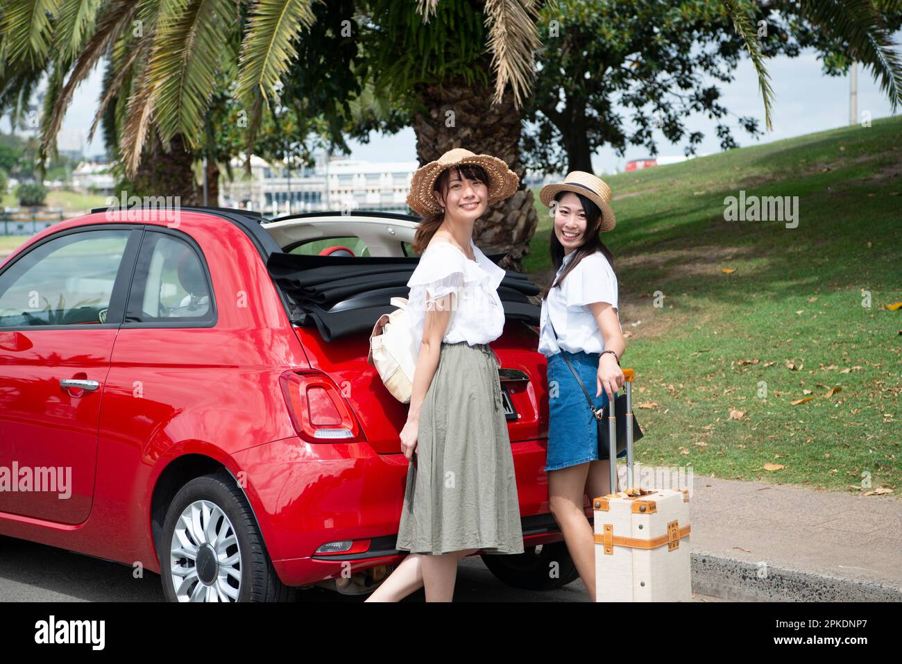 Two women standing in front of a red car Stock Photo - Alamy