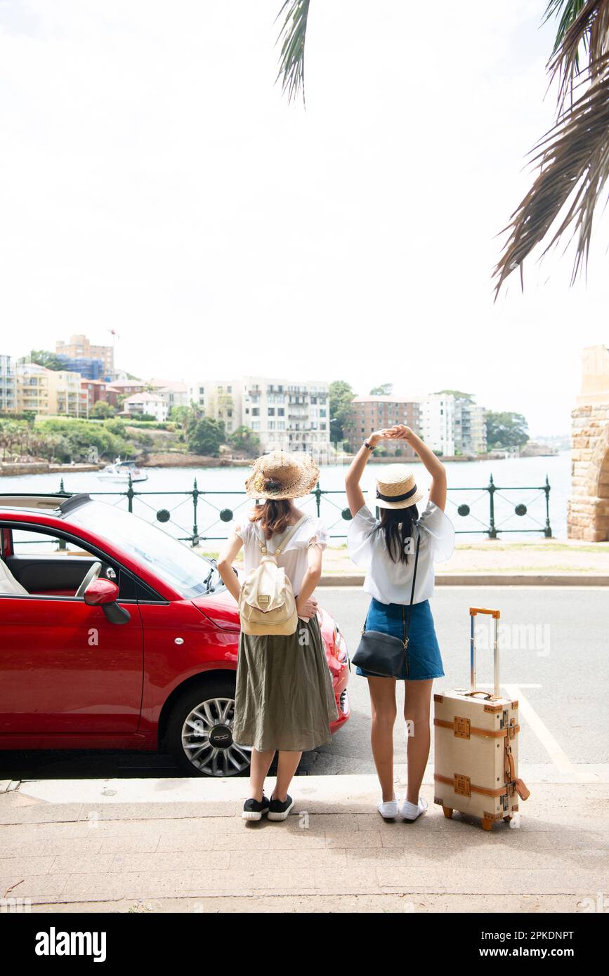 Back view of two women standing in front of a red car Stock Photo