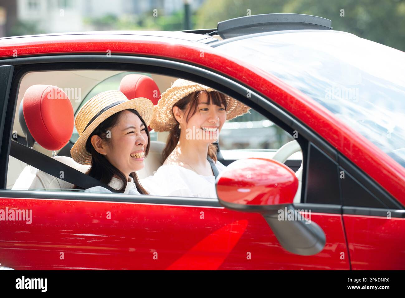 Two women laughing in a red car Stock Photo - Alamy
