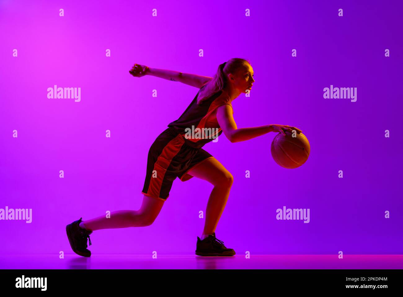 Young girl, concentrated female basketball player in motion, dribbling