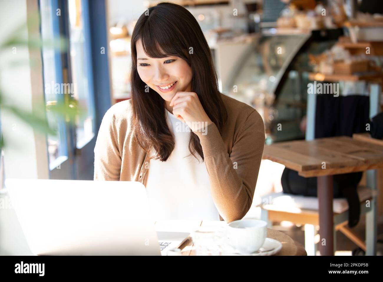Woman working at a café using a computer Stock Photo