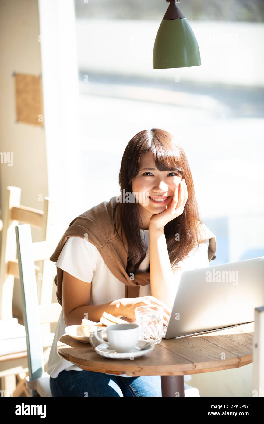 Woman working at a café using a computer Stock Photo