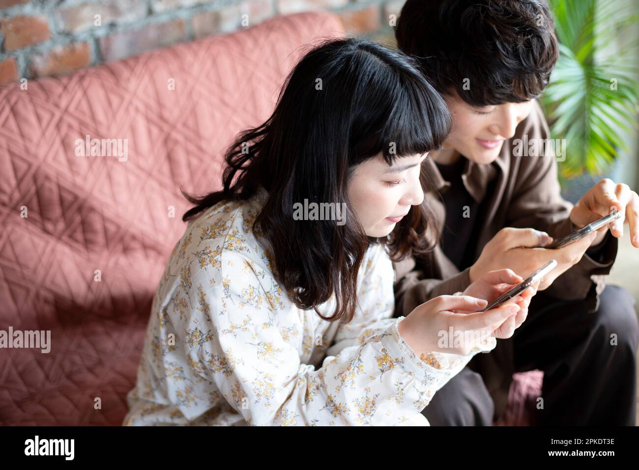 Couple looking at their phones at home Stock Photo