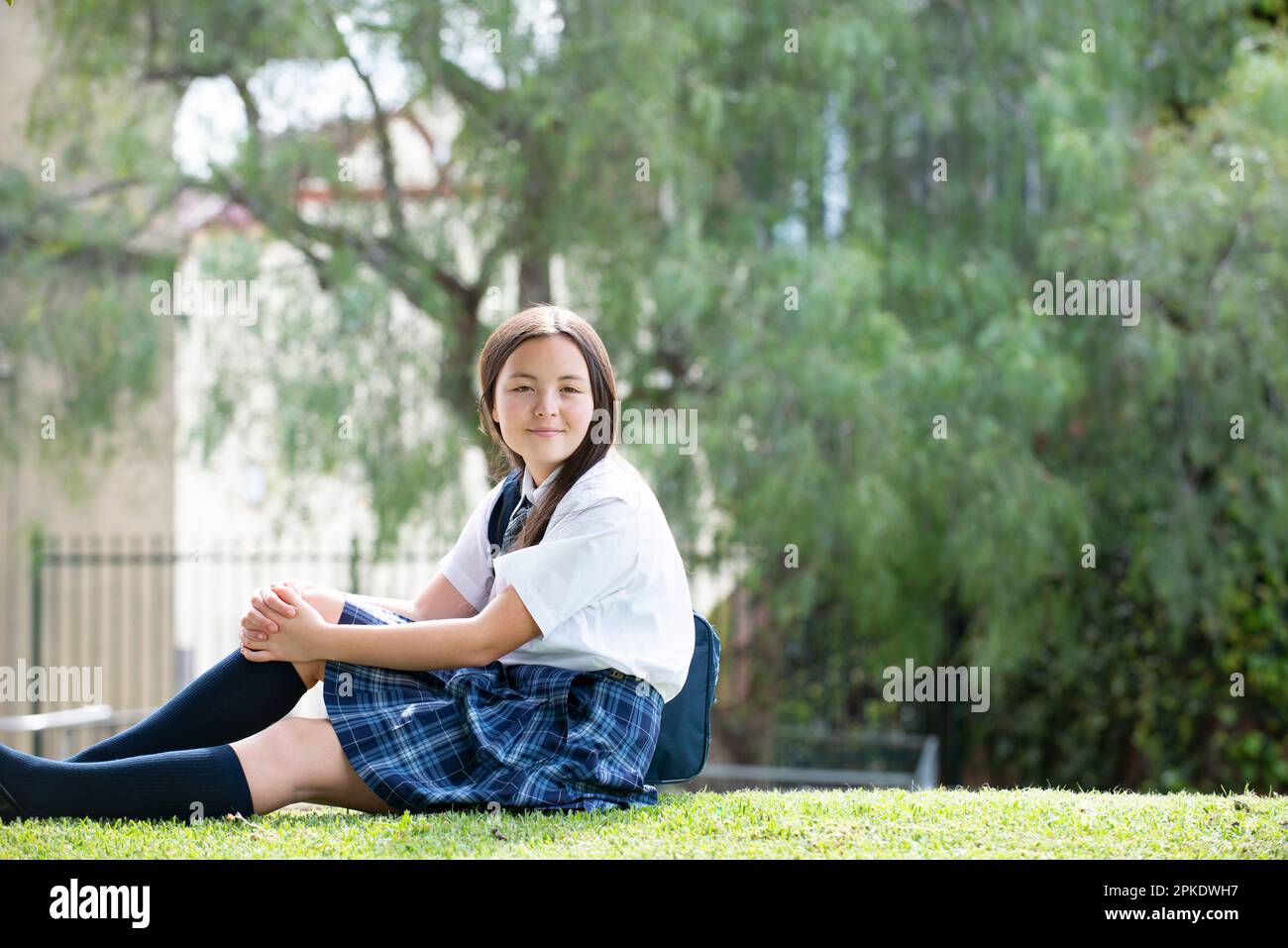 Female student in school uniform sitting on the lawn Stock Photo - Alamy