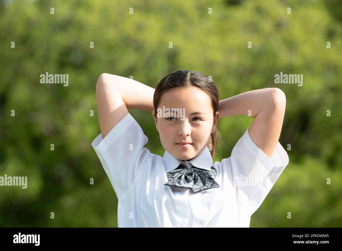 Photo inspiration: Picture Idea: Female Student In School Uniform Tying Her Hair Stock Photo