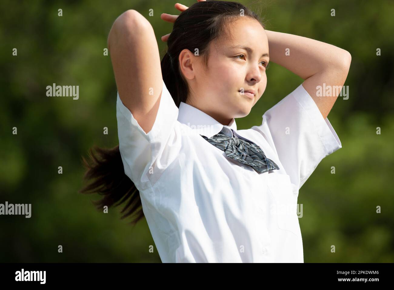 Visual Reference: Female Student In School Uniform Tying Her Hair Stock Photo