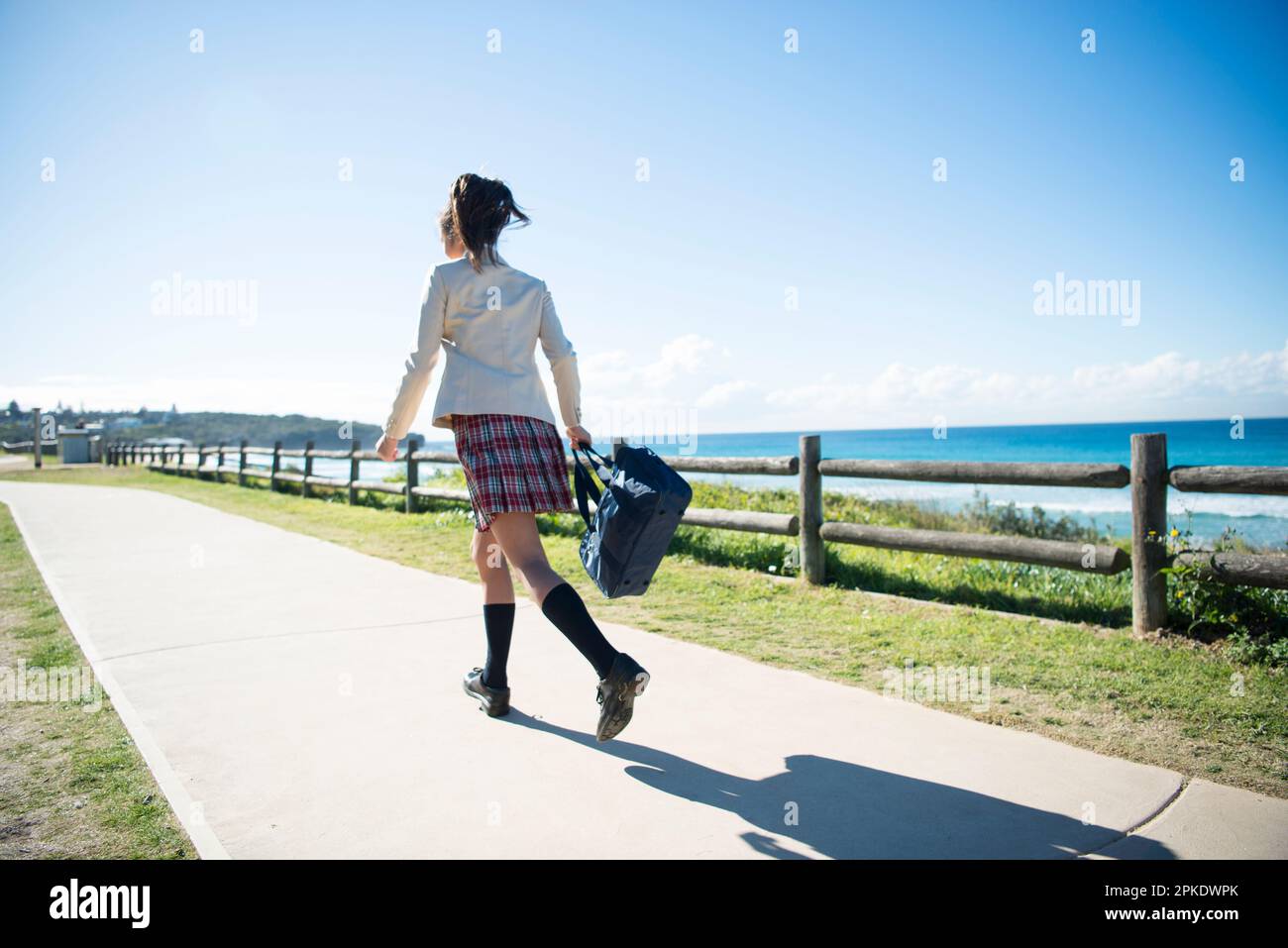 Schoolgirl in school uniform running along the beach Stock Photo Alamy