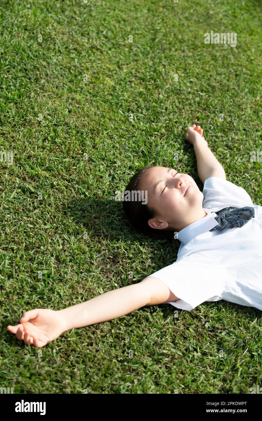 Schoolgirl in school uniform lying on the grass Stock Photo - Alamy