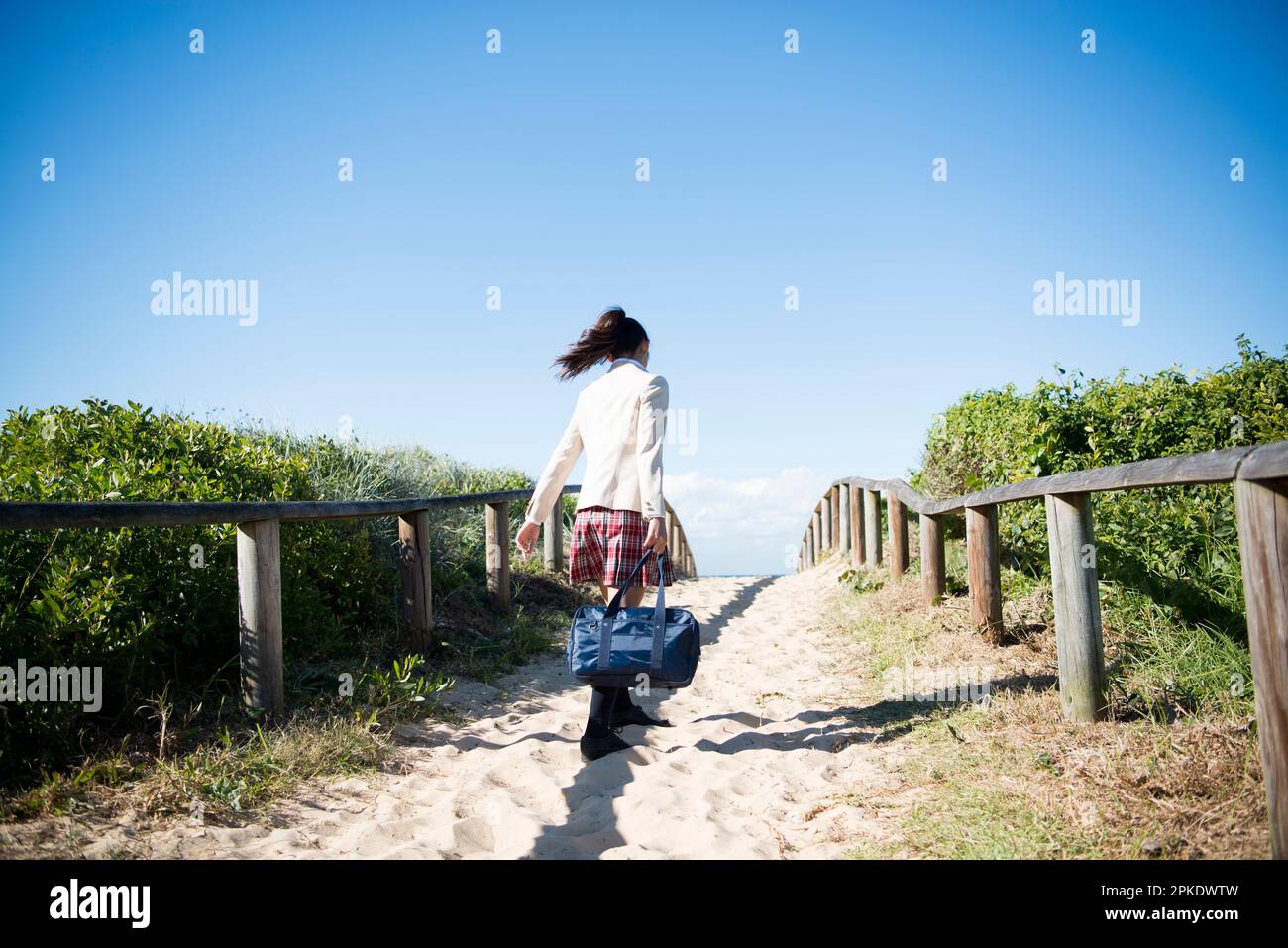 Schoolgirl in school uniform walking on the beach Stock Photo - Alamy