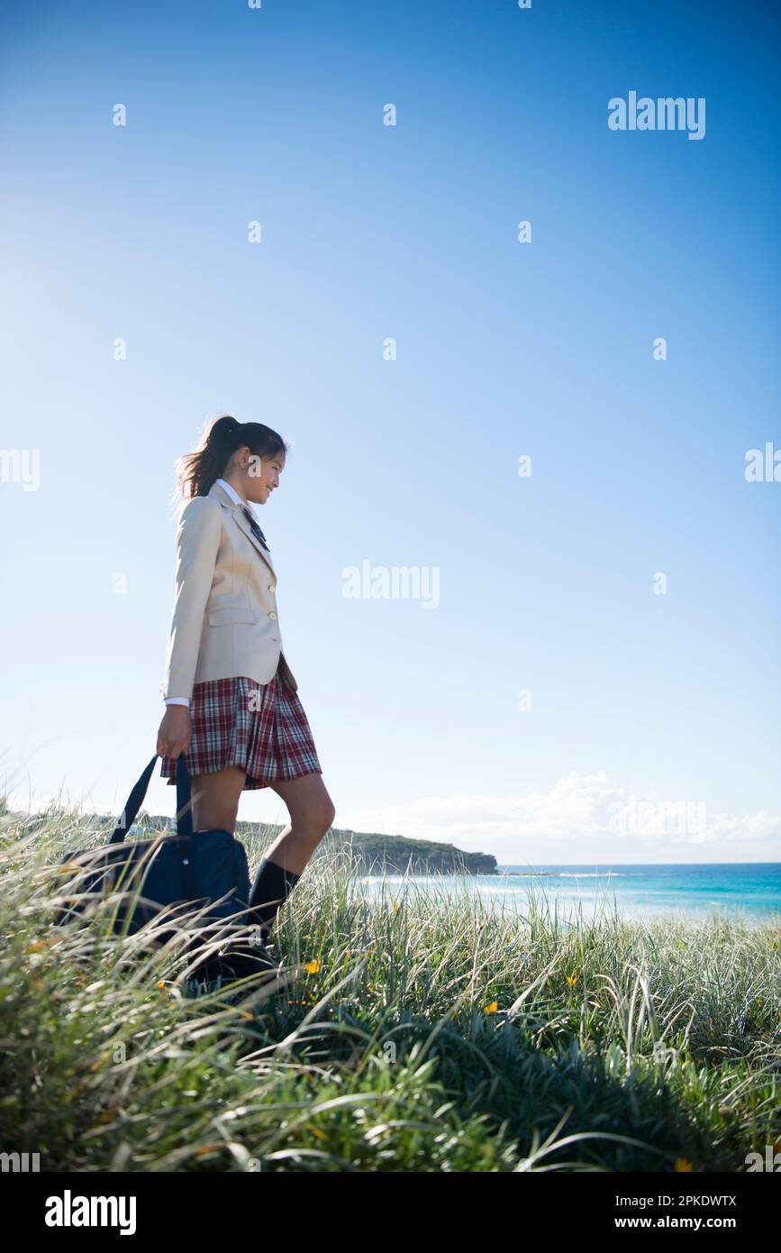Schoolgirl in school uniform walking on the grass Stock Photo - Alamy